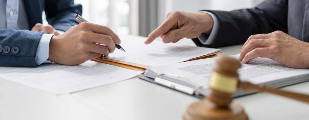 Close up of hands from people with suits pointing at paperwork.